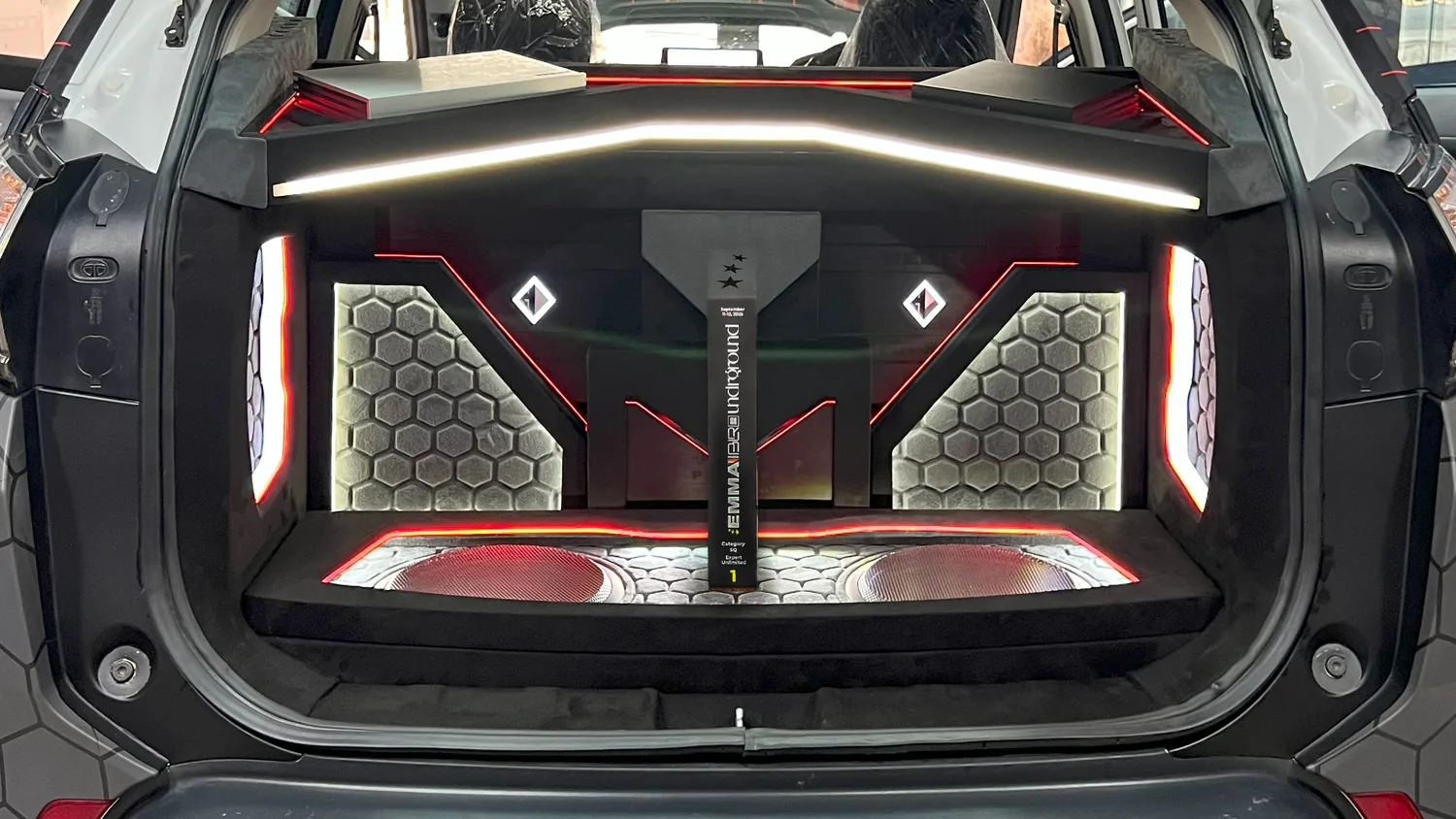 An SUV boot rebuilt as a hexagon-panelled amplifier rack picked out in red LED, an LED bar across the tailgate